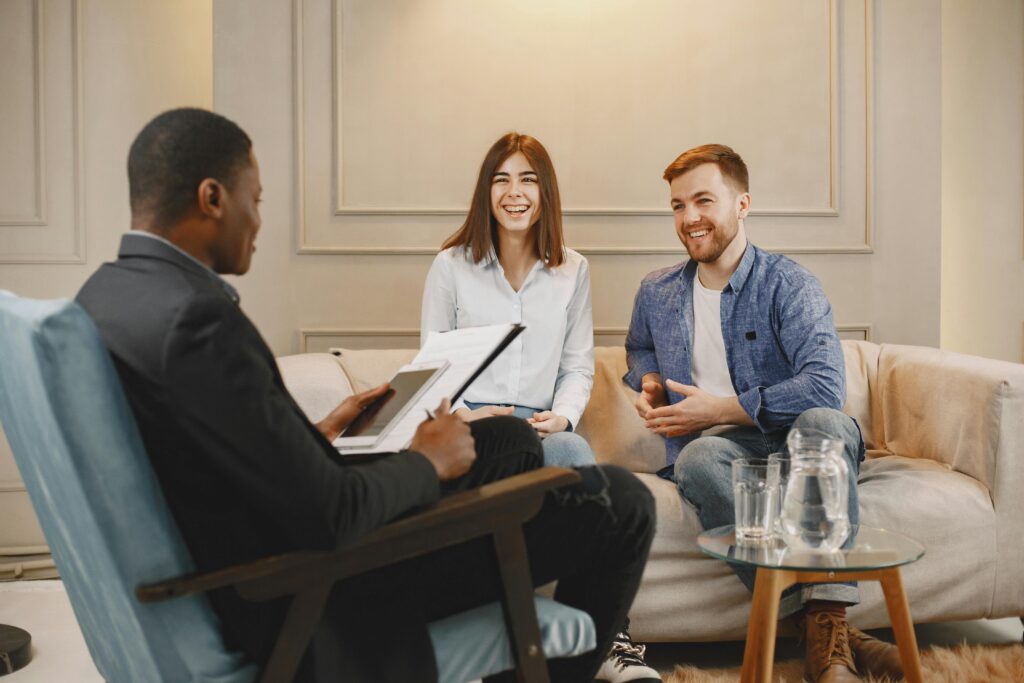 A happy couple engages with an advisor during a consultation in a cozy living room.