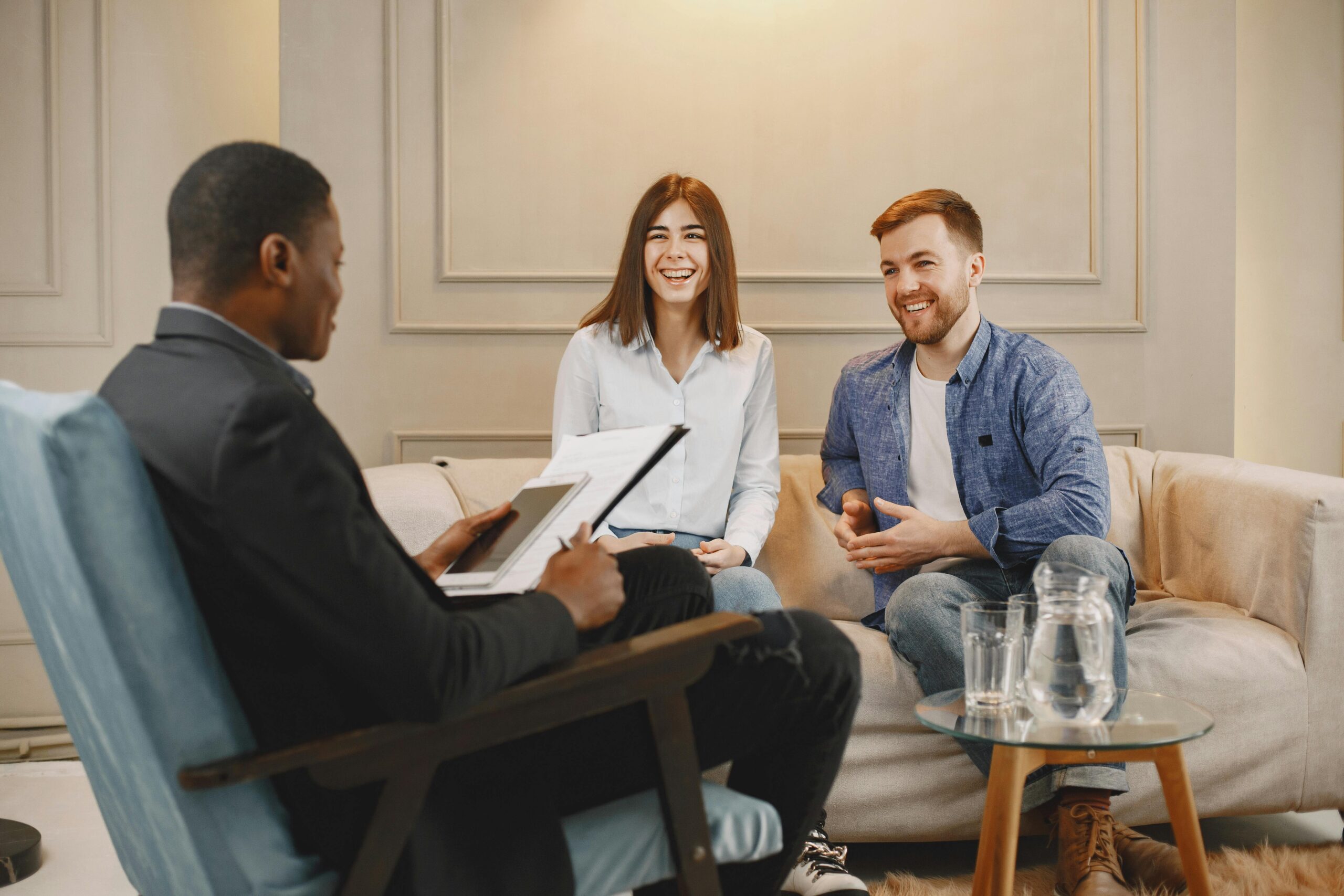 A happy couple engages with an advisor during a consultation in a cozy living room.